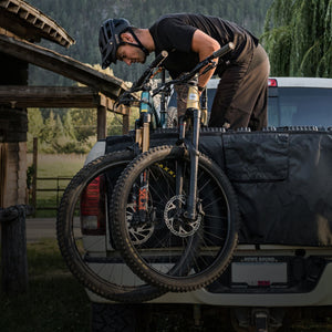EVOC tailgate pad being loaded by mountain biker in the back of a truck mobile view