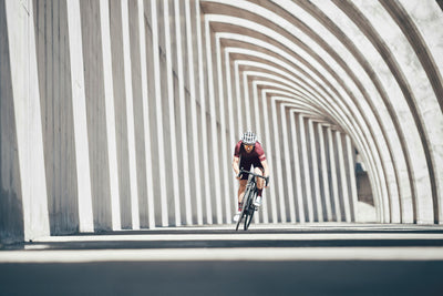 EVOC athlete sprinting on a road bike amongst shadow contrasting concrete architecture