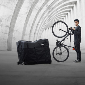 EVOC Bike Travel Bag next to man holding bike upright homepage slider mobile view