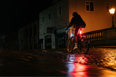 Cyclist riding bicycle with lights on a dark street