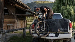 EVOC tailgate pad on pick up truck being loaded by mountain biker