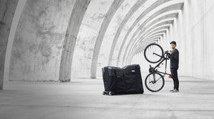 EVOC Bike Travel Bag next to man holding bike upright homepage slider