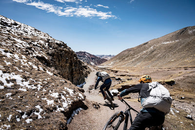 Mountain bikers with EVOC backpacks riding down trail in the Peruvian Andes