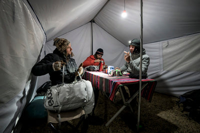 Riders sitting in kitchen tent discussing prototype EVOC backpack