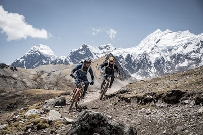 Mountain bikers with EVOC packs riding down trail with glaciers in background