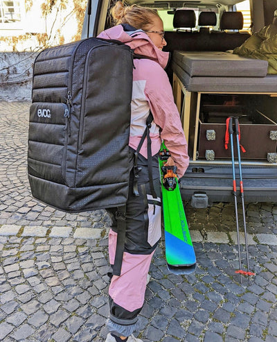 EVOC Gear Backpack being worn by woman in ski clothing carrying skis